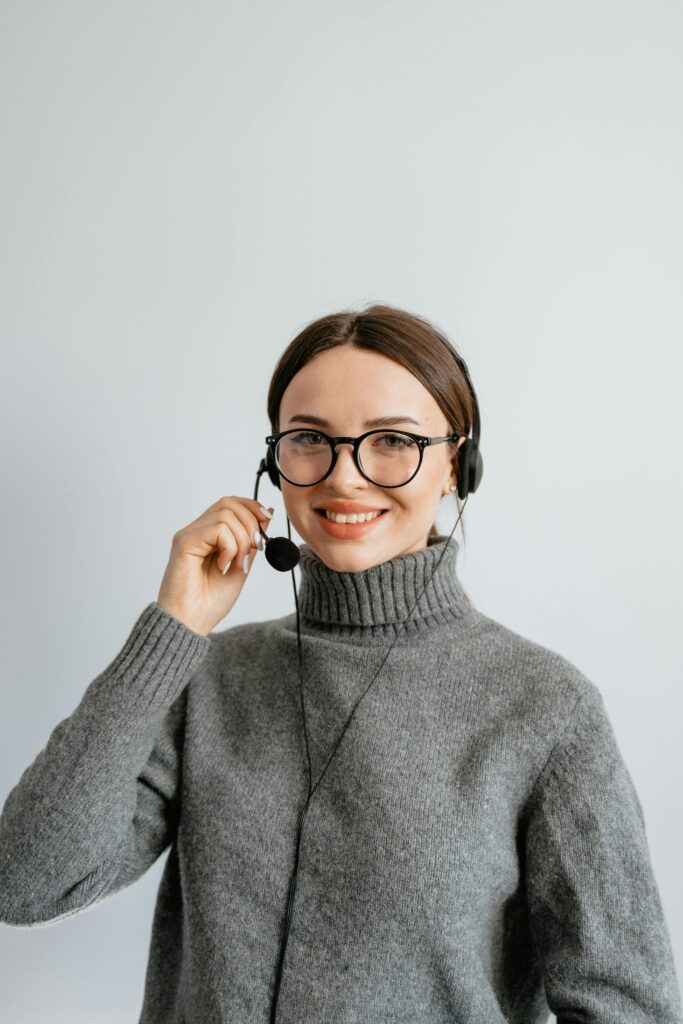 pexels-photo-7709235-7709235 Friendly customer support woman smiling while wearing a headset in the office.